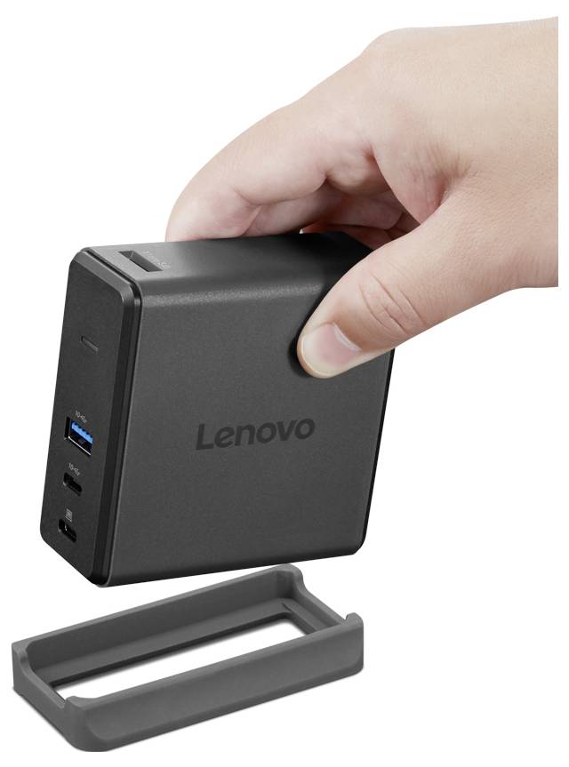 Ruka držící kompaktní stolní počítač Lenovo s více porty, doplněný odnímatelnou šedou podstavou pod ním.