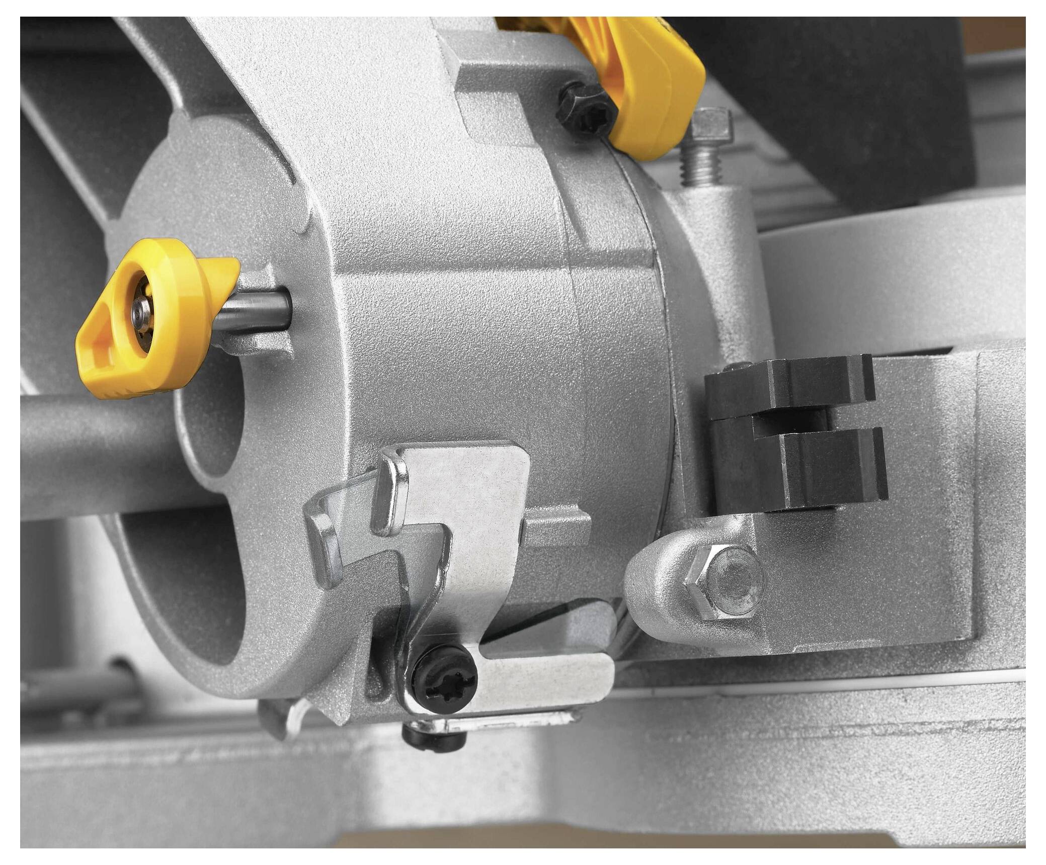 Detailní snímek součástky kruhové pily s kovovým pouzdrem a seřizovacím mechanismem se žlutými plastovými prvky pro funkčnost.
