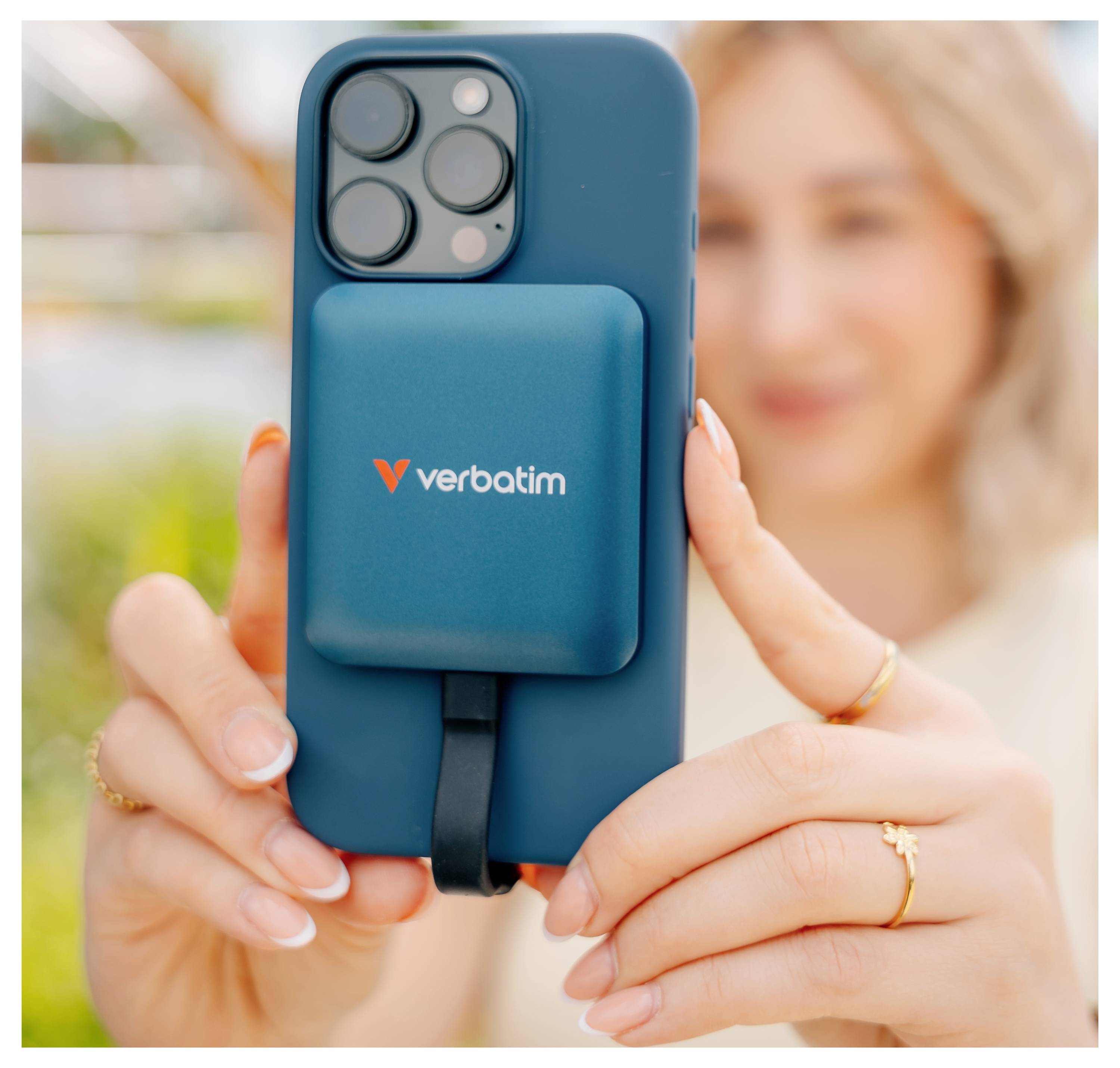 Žena držící tyrkysový smartphone s magnetickou bateriou Verbatim připevněnou na zadní straně, zobrazeno v detailním záběru.