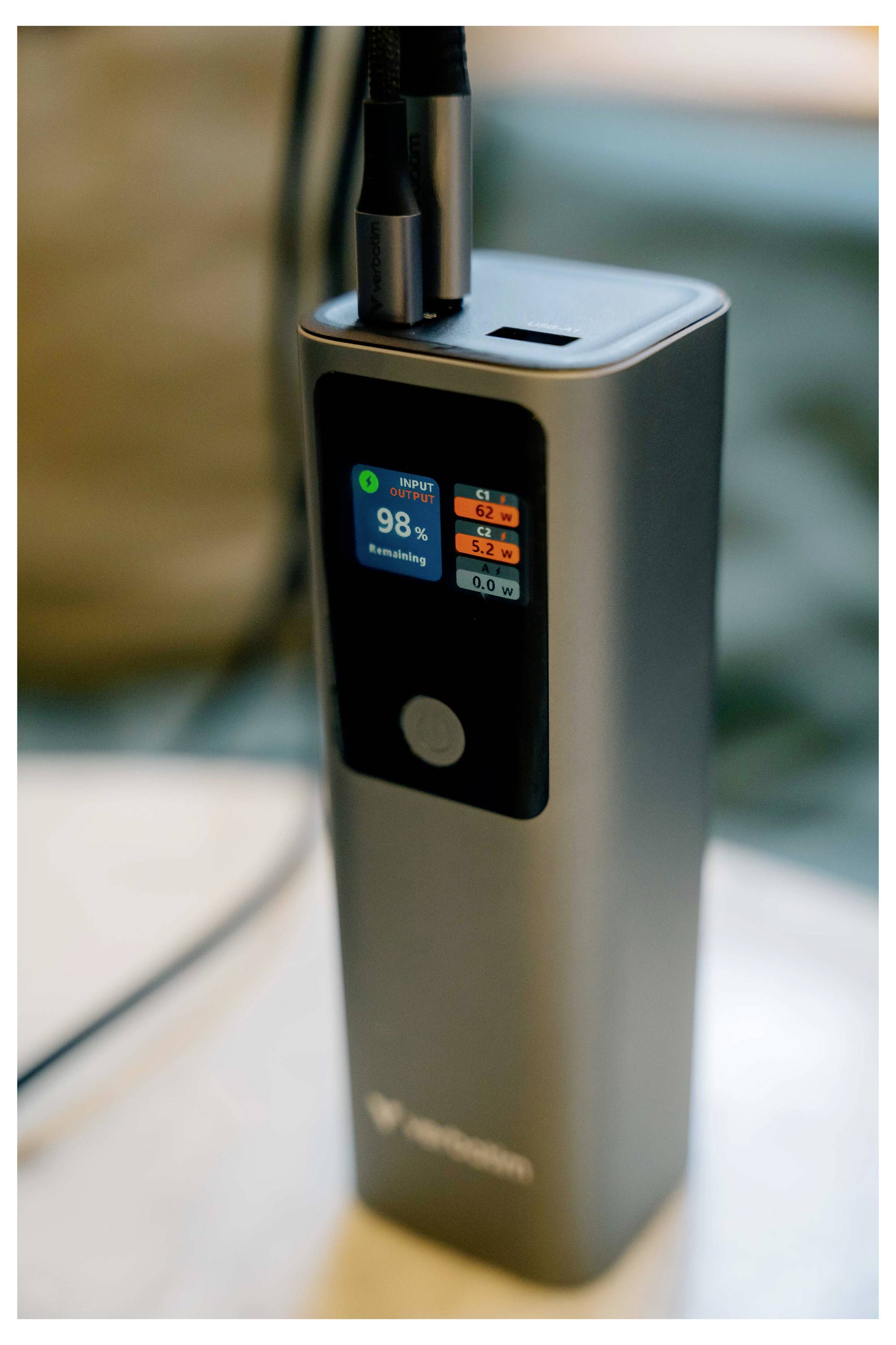Přenosné zařízení na vaping s nabíjením přes USB-C, s malou obrazovkou zobrazující baterii na 98% a indikátory úrovně elektronické tekutiny.