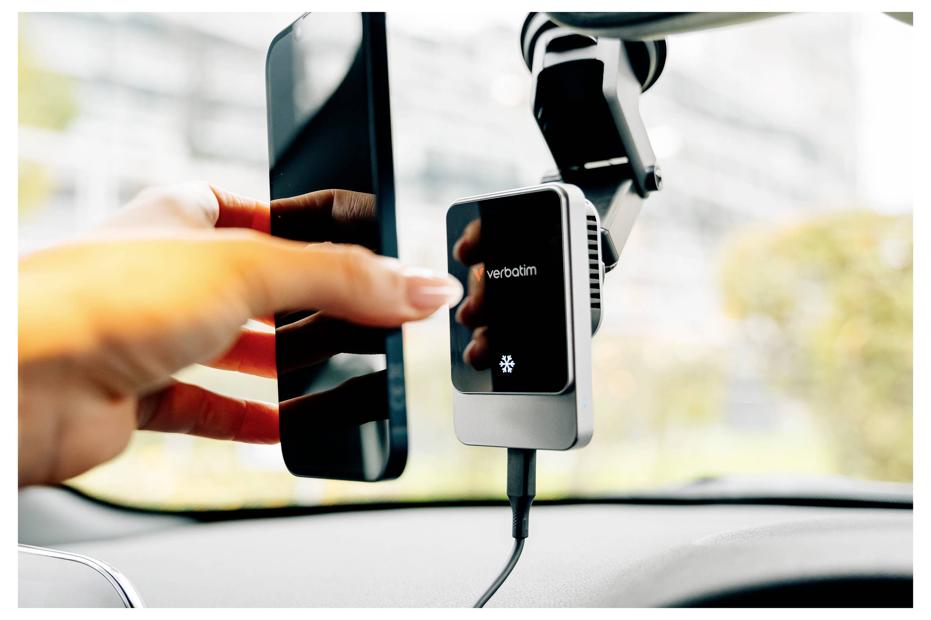 Ruka zapíchne telefon do automobilem připevněné bezdrátové nabíječky Verbatim vedle čelního skla.