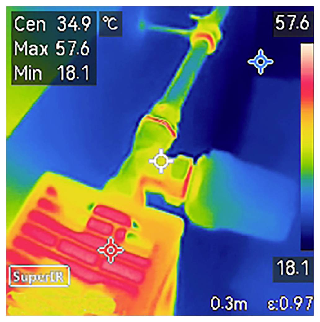 Tepelný snímek zobrazující teplotní rozsah od 18,1 °C do 57,6 °C. Ústředním zaměřením je 34,9 °C na mechanické součásti s tepelným gradientem.
