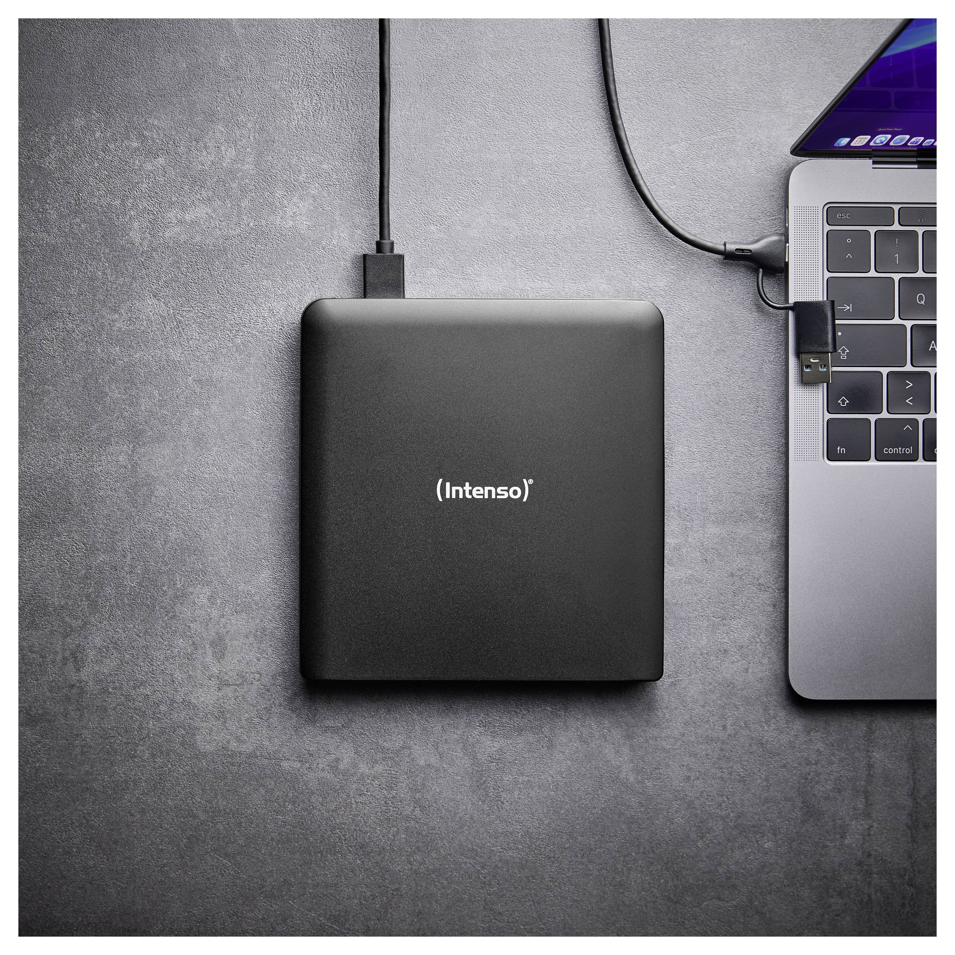Externí pevný disk s označením 'Intenso' je připojen k notebooku pomocí kabelu. Scéna je umístěna na šedém povrchu a znázorňuje nastavení úložiště dat.