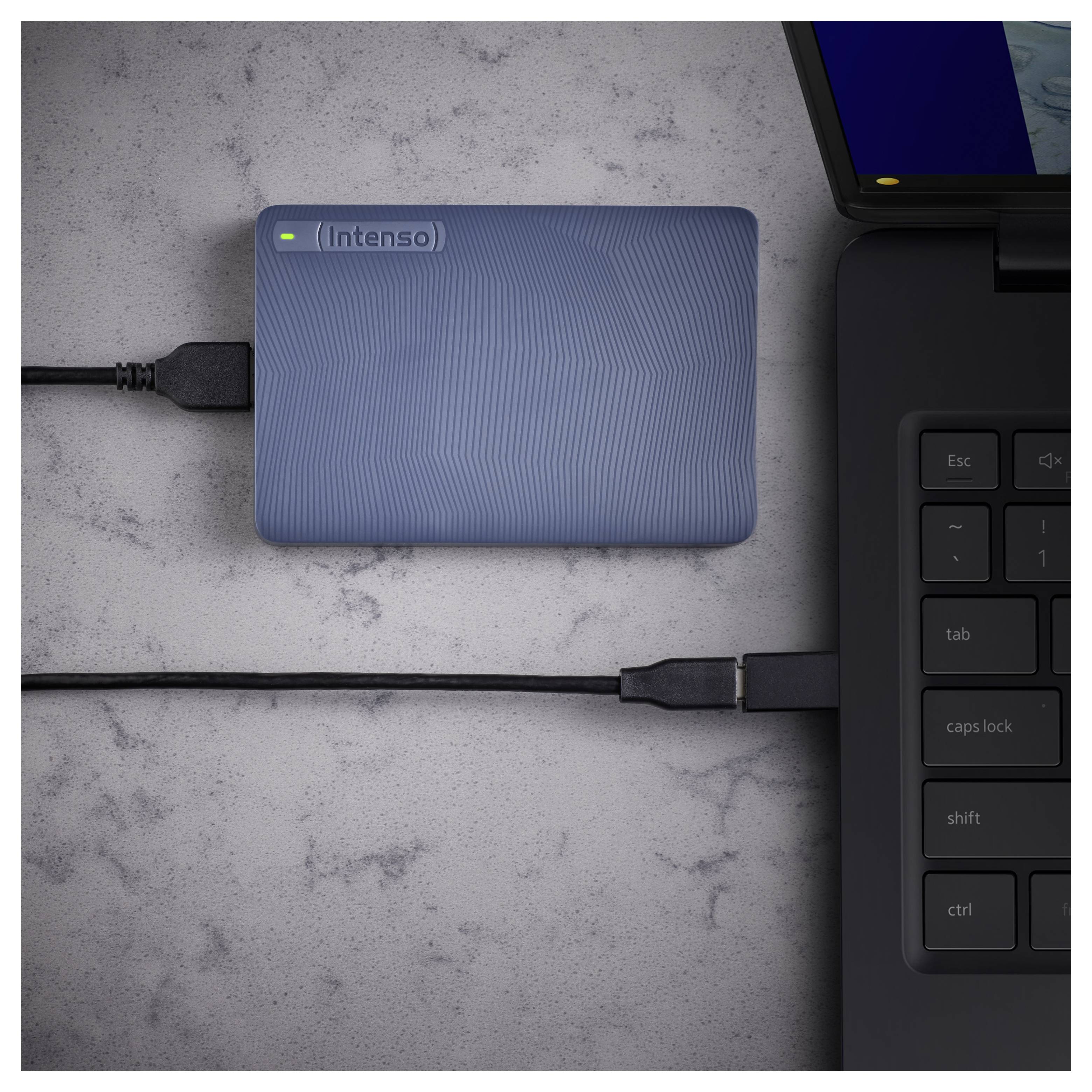 Vnější modrý pevný disk připojený k černému notebooku prostřednictvím kabelu USB na šedém povrchu, přičemž notebook je částečně viditelný na pravé straně.