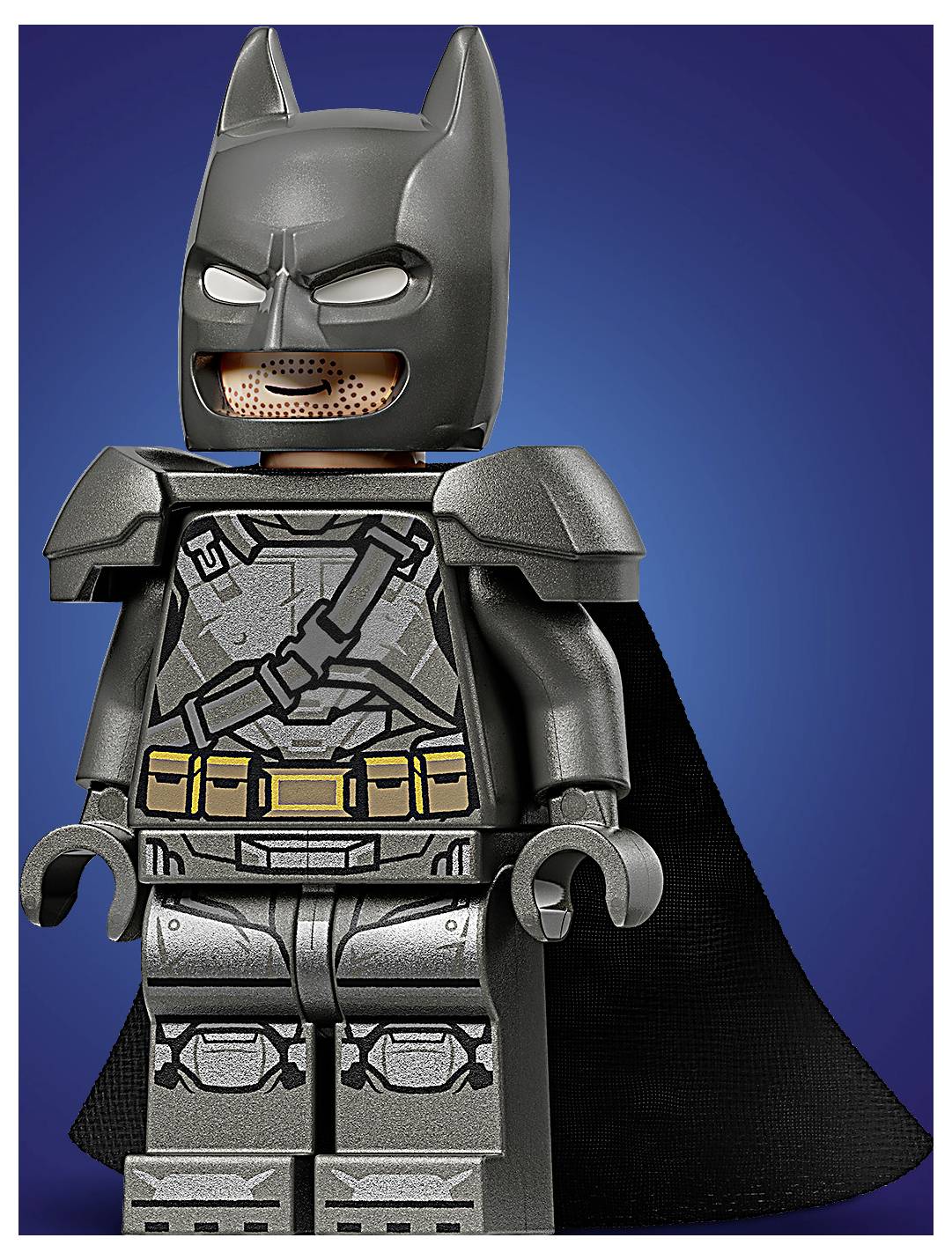 Figurka LEGO podobná superhrdinovi s maskou podobnou летучí mysši a pláštěm, v šedém obleku s páskem s pomůckami, stojící proti modrému pozadí.