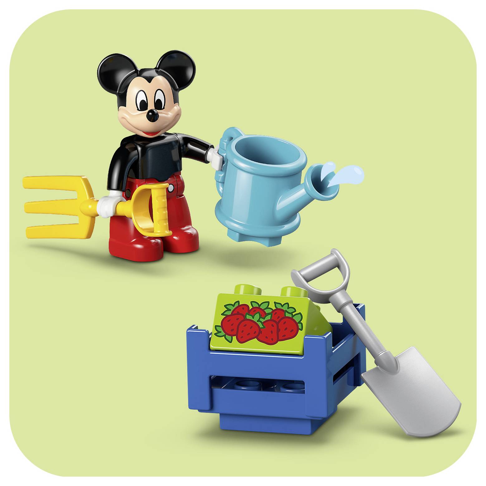 Figurka LEGO Mickey Mouse s kropenkou a viděly v rukou stojí vedle bedny se jahodami a lopatou na zeleném pozadí.