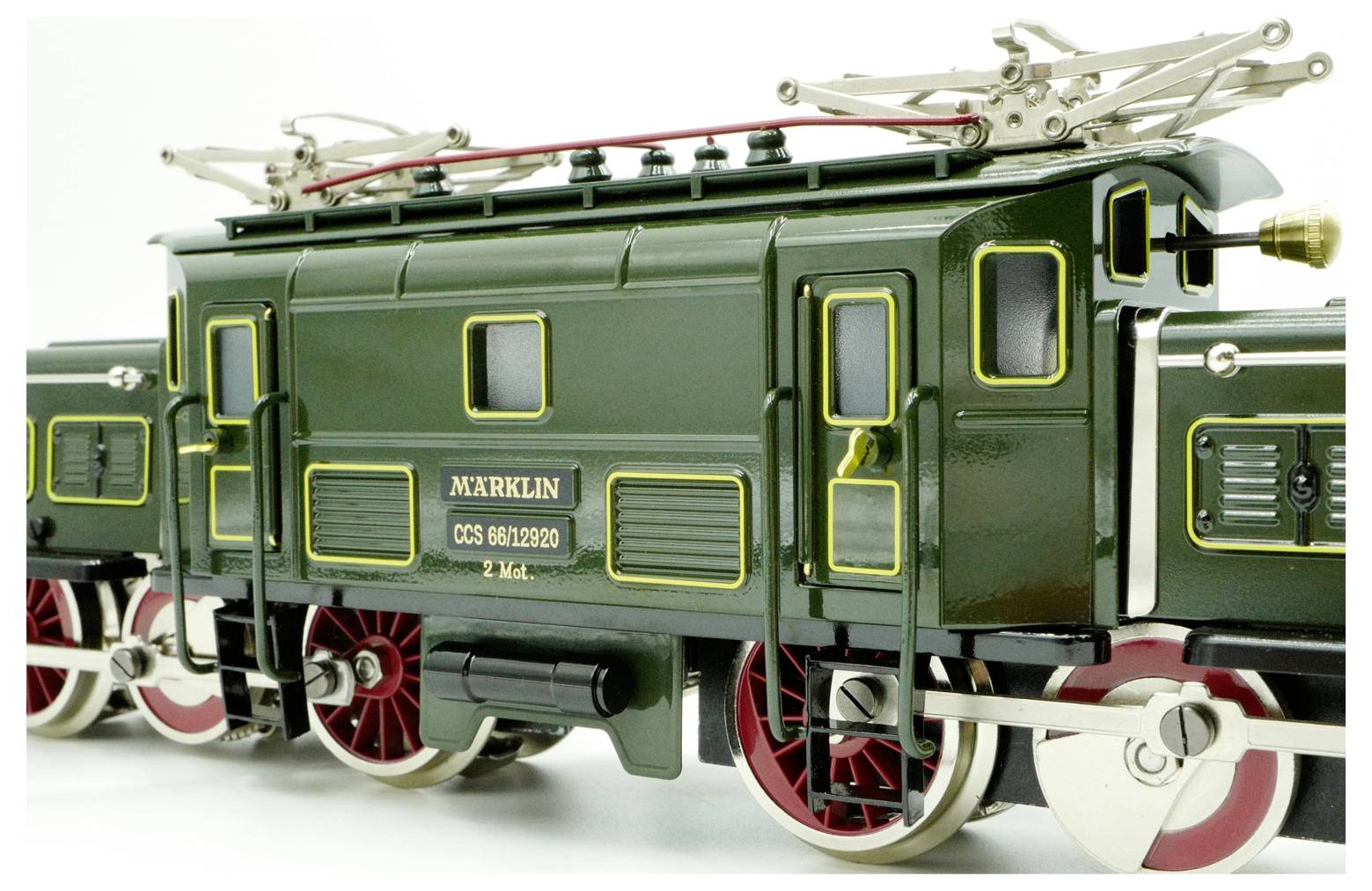 Detailní modelový vlak představující složitý design a zpracování značky Märklin. Mezi charakteristiky patří zelený exteriér, červená kola a jemnou kovárenskou práci.