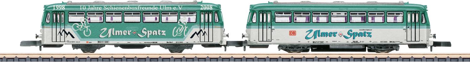 Dva zeleno-bílé elektrické historické tramvaje na kolejích se nápisem "Nature-Spots" na stranách, vykazující retro design.