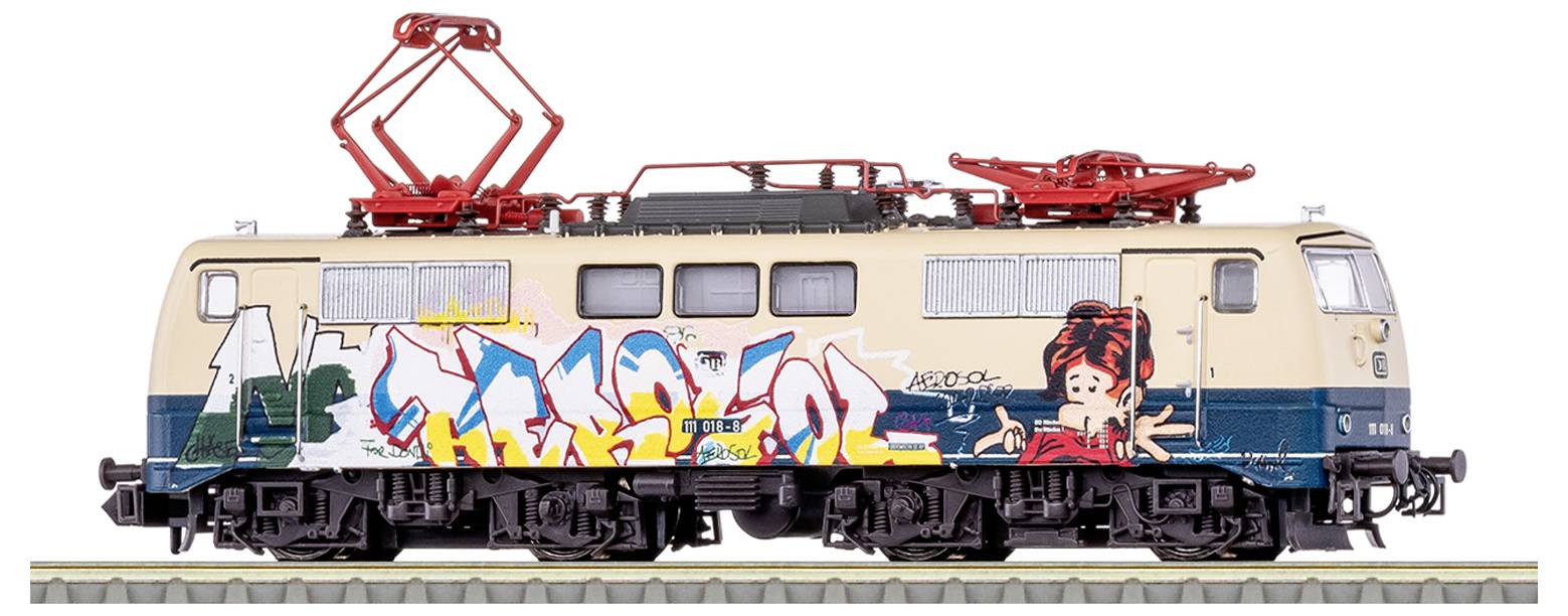 Model historické elektrické lokomotivy s barevným graffiti uměním na boku, obsahující abstraktní tvary a kreslené postavy.