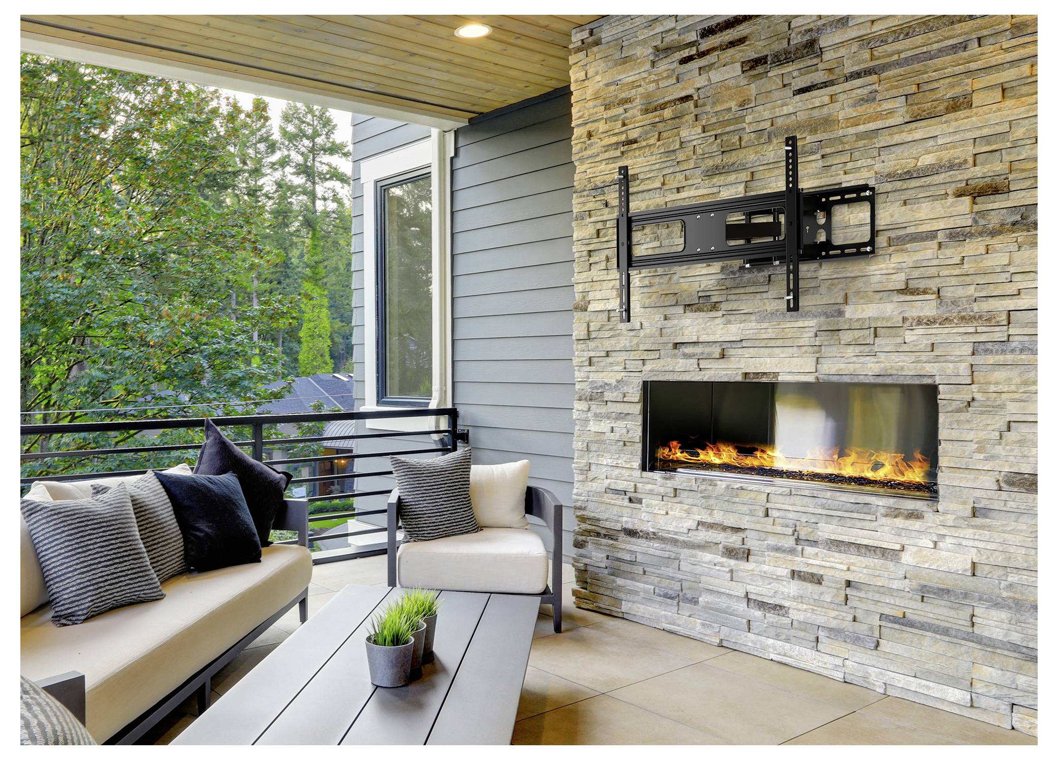 Venkovní terasa s kamenným krbem, polstřeným sezením a stolem. Zeleň viditelná skrz zábradlí zvyšuje útulnou atmosféru.