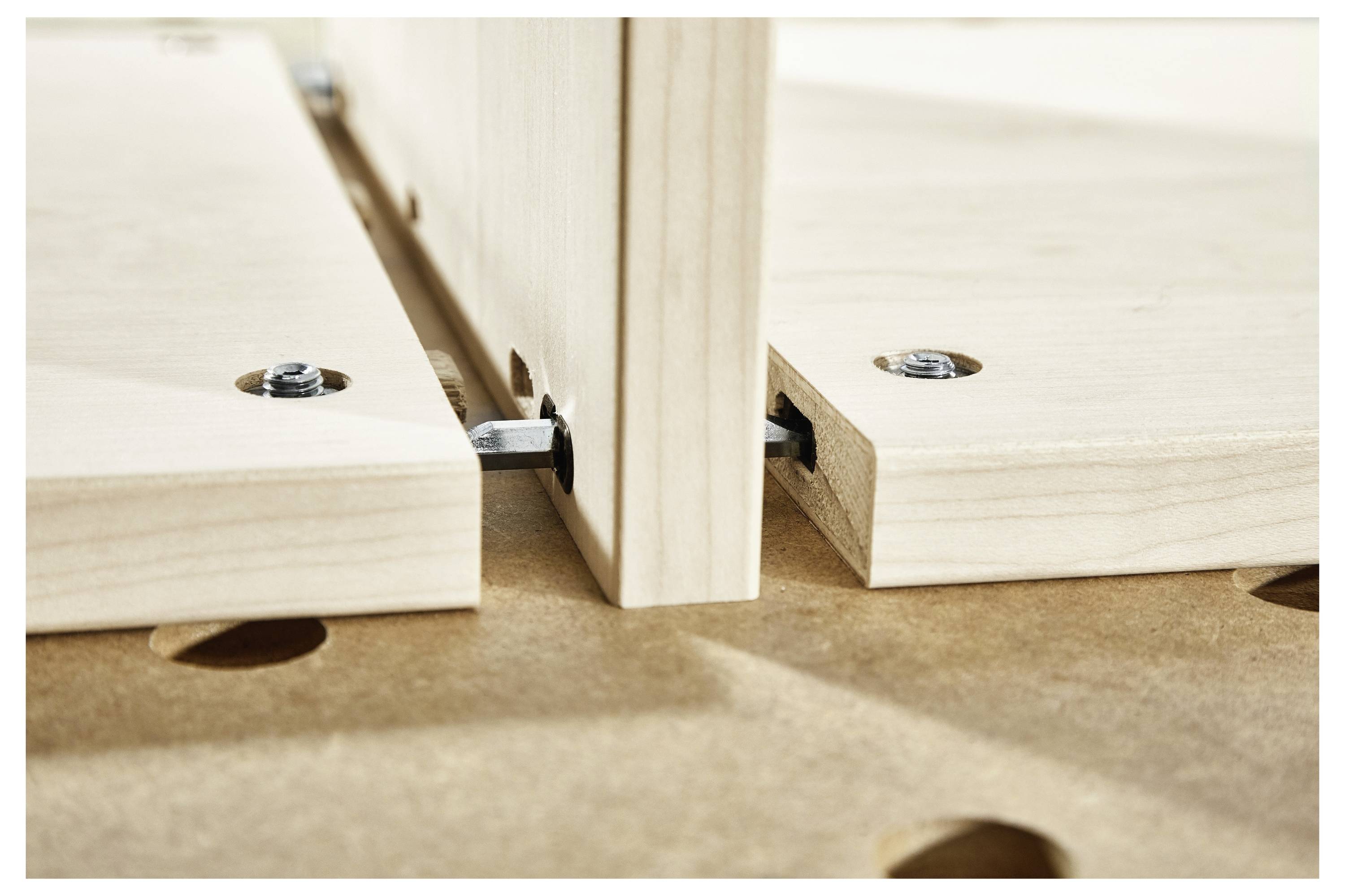 Detail fotografií dřevěných desek spojovaných pomocí konektorů, zdůrazňující montáž DIY nábytku nebo woodworkingový detail.