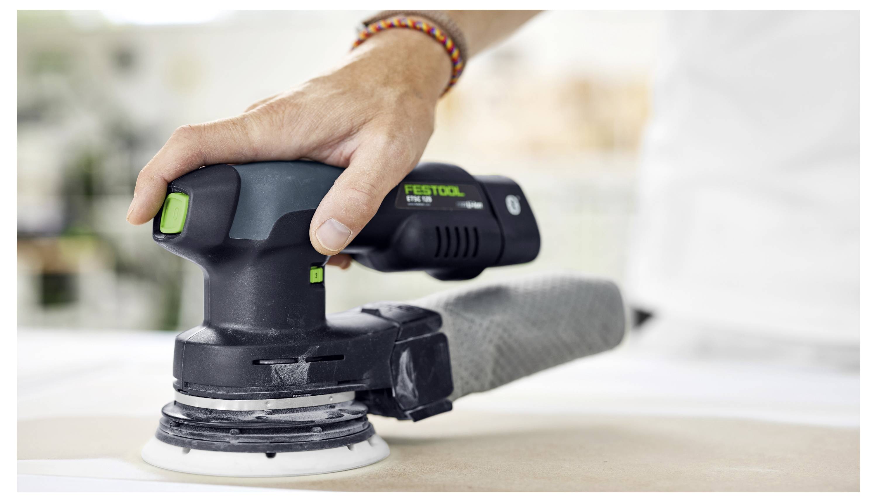 Osoba používá Festool elektrickou brusku na rovném povrchu, zaměřuje se na vyhlazování nebo formování materiálu.