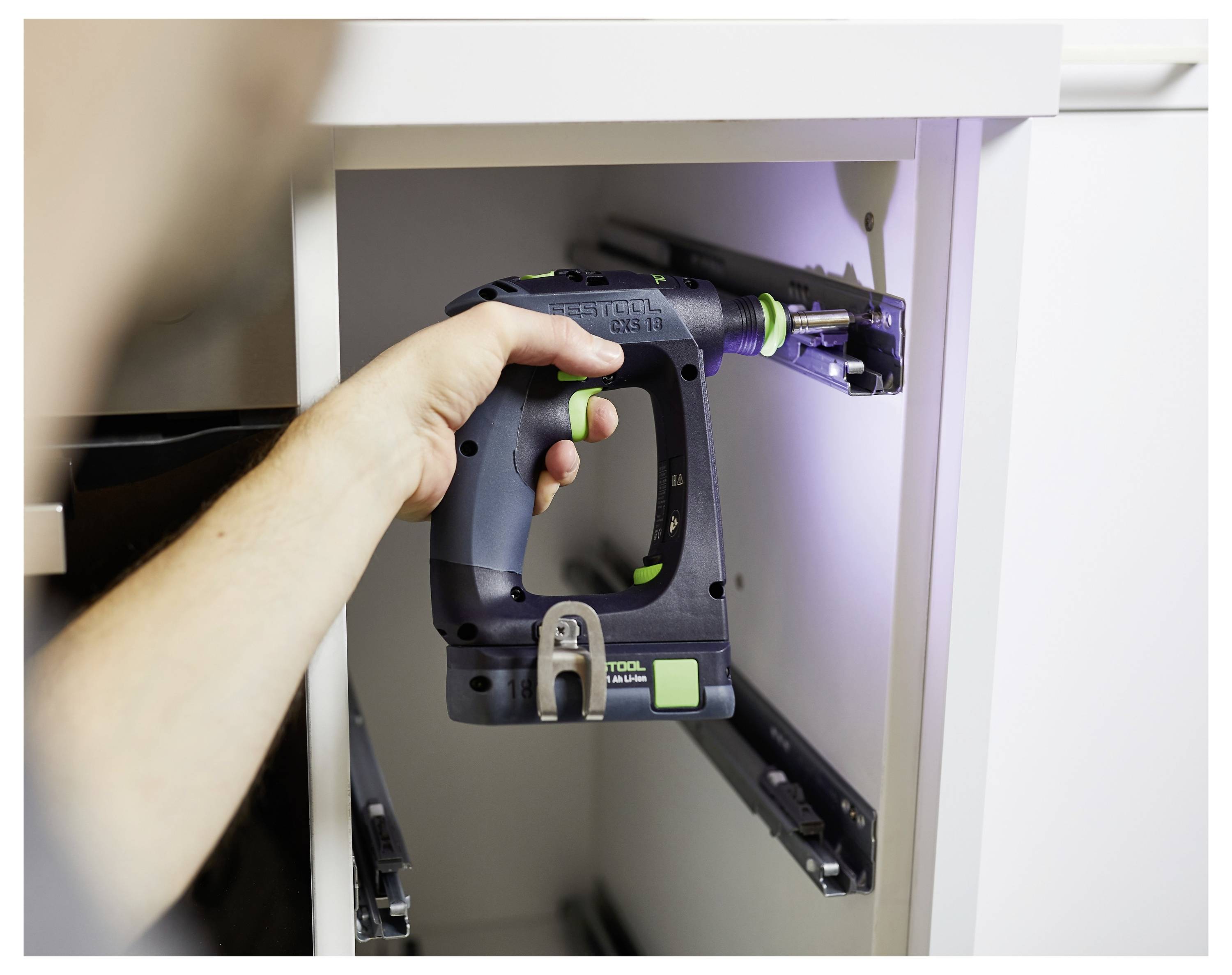 Osoba instaluje posuvný systém zásuvky do kuchyňské skříně pomocí bezdrátového elektrickéhonářadí s důrazem na přesnost a zarovnání.
