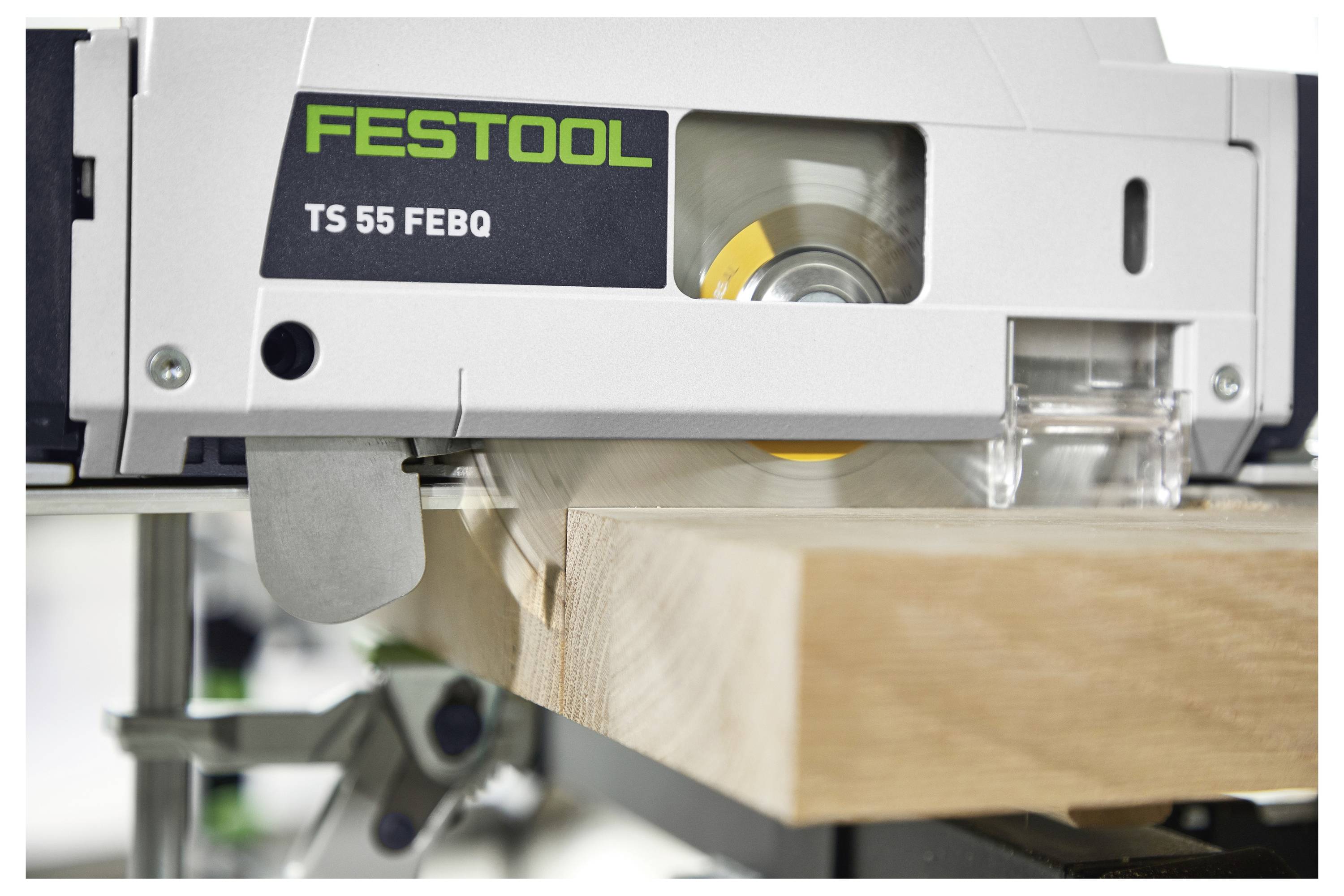 Detailní záběr cirkulární pily Festool TS 55 FEBQ řezající dřevěné prkno, ukazující pohybující se kotouč a viditelné logo značky.