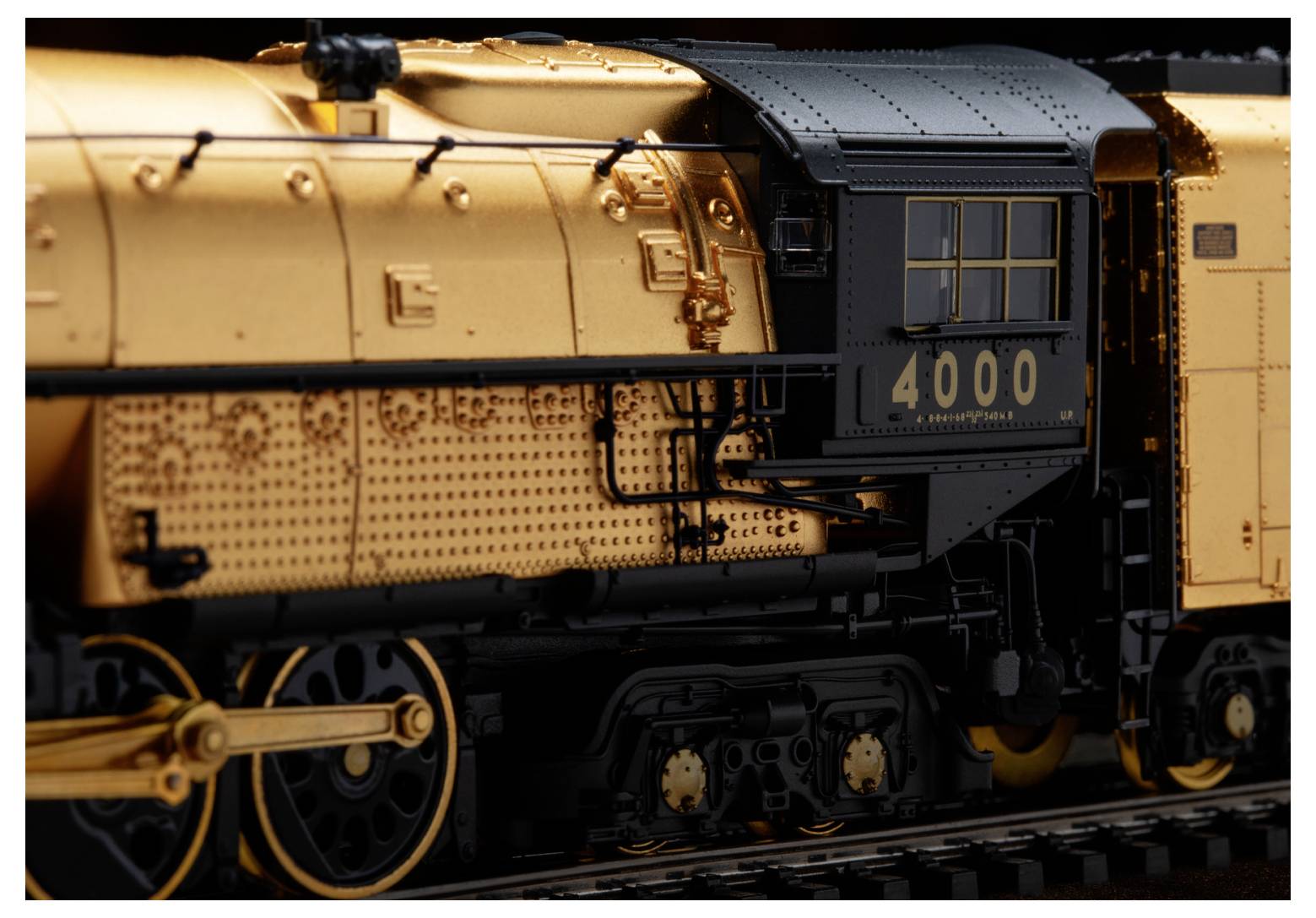 Detailní snímek modelového vlakového lokomotivy se zlatým a černým exteriérem a číslem '4000' na boku.