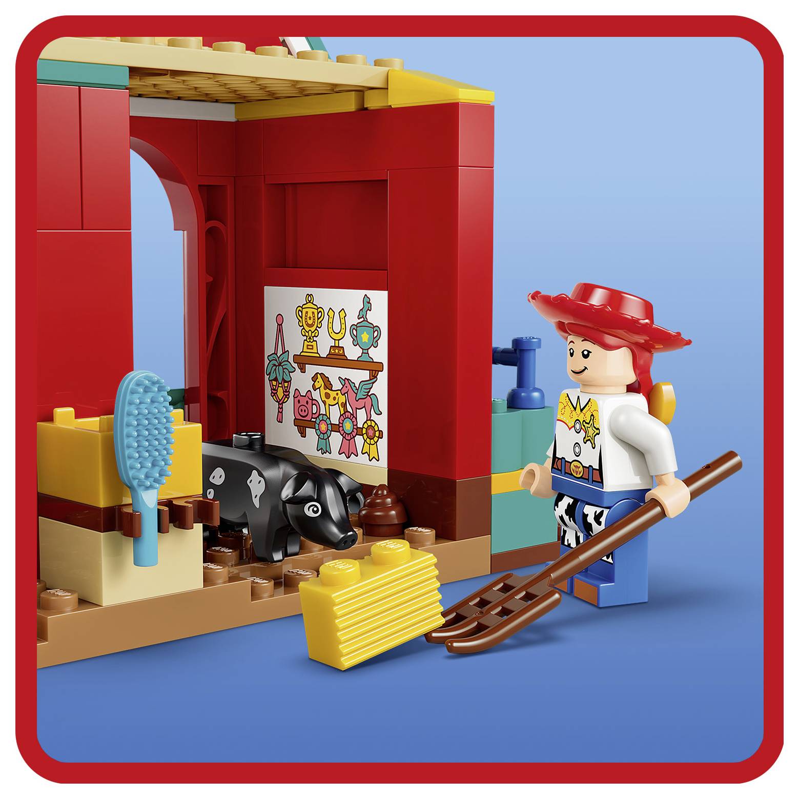 Scéna s LEGO hračkou Jessie z Toy Story s černobílou krávou, metlou, kartáčem a červeným pozadím stáje.