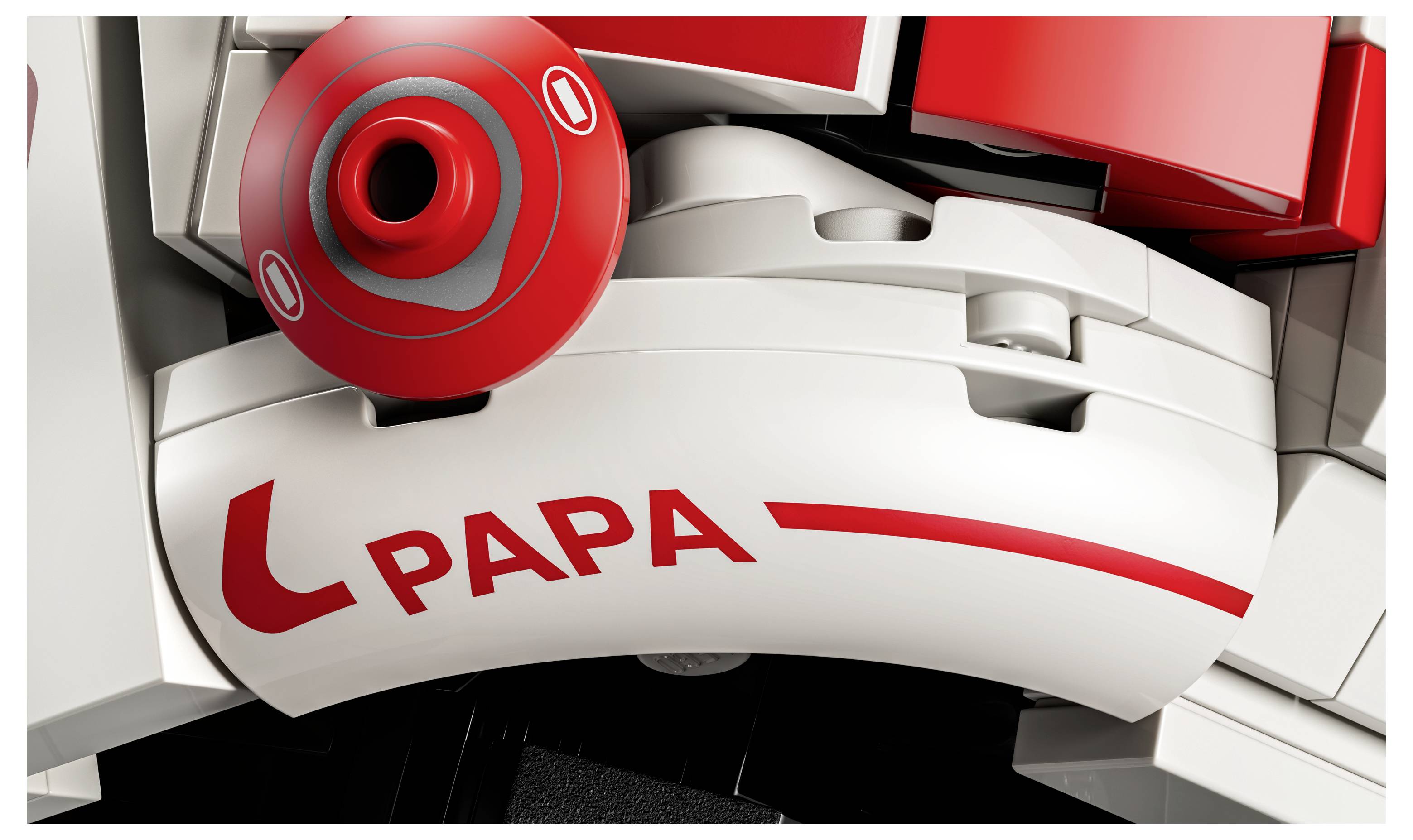 Detailní záběr bílé a červené plastové robustické hračky s nápisem „PAPA" vytištěným na jedné z jejích zakřivených částí.