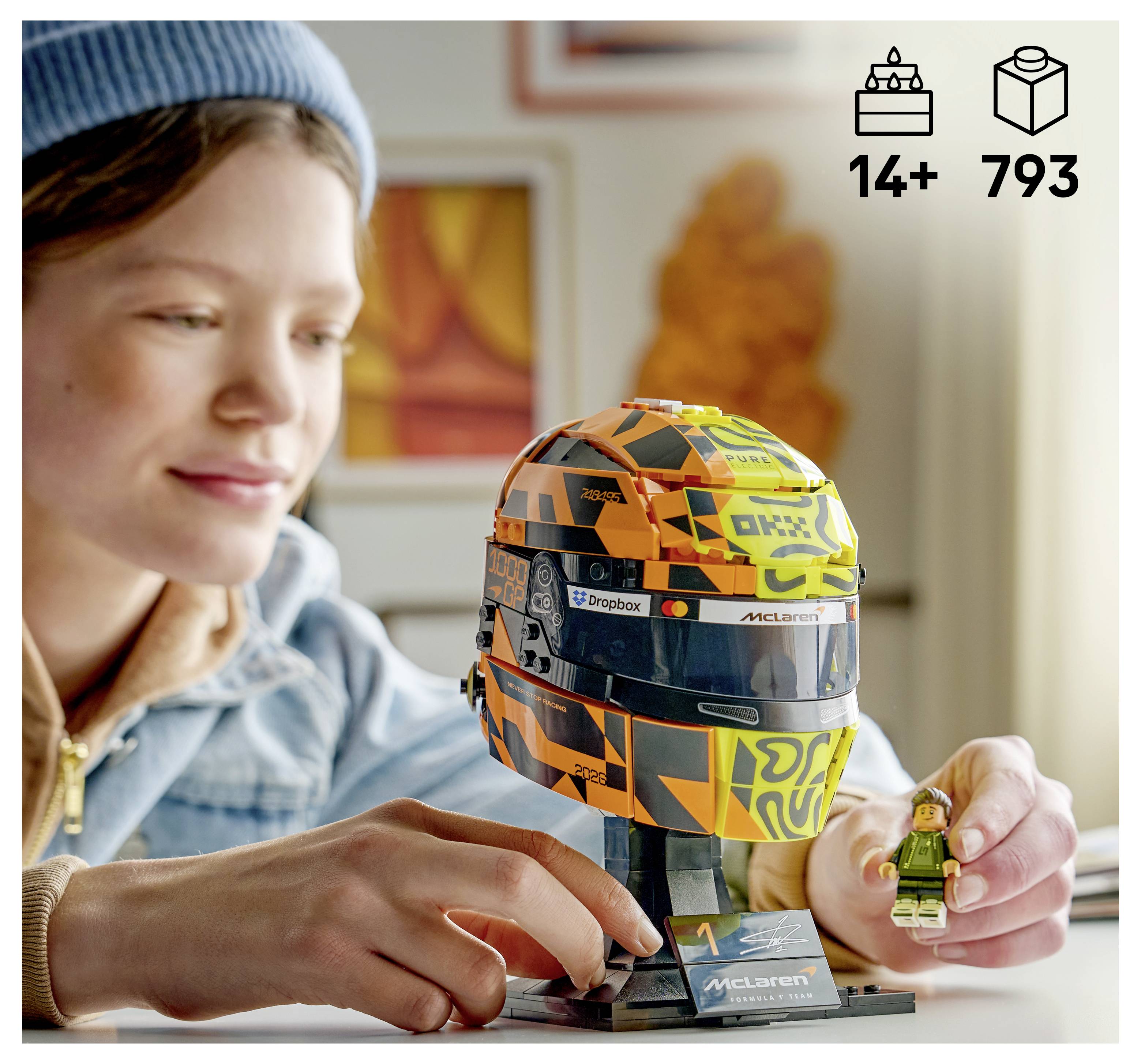 Dítě skládající helmou LEGO McLaren Formule 1 s figurkou; obal ukazuje věk 14+ a 793 dílů.