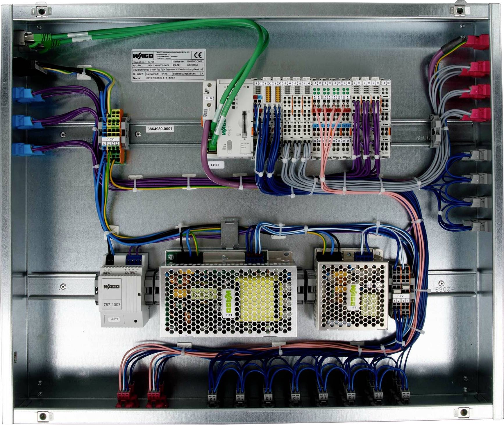 Otevřený kovový elektrický ovládací panel s různobarevnými vodiči připojenými k svorkám, který ukazuje složité vedení.