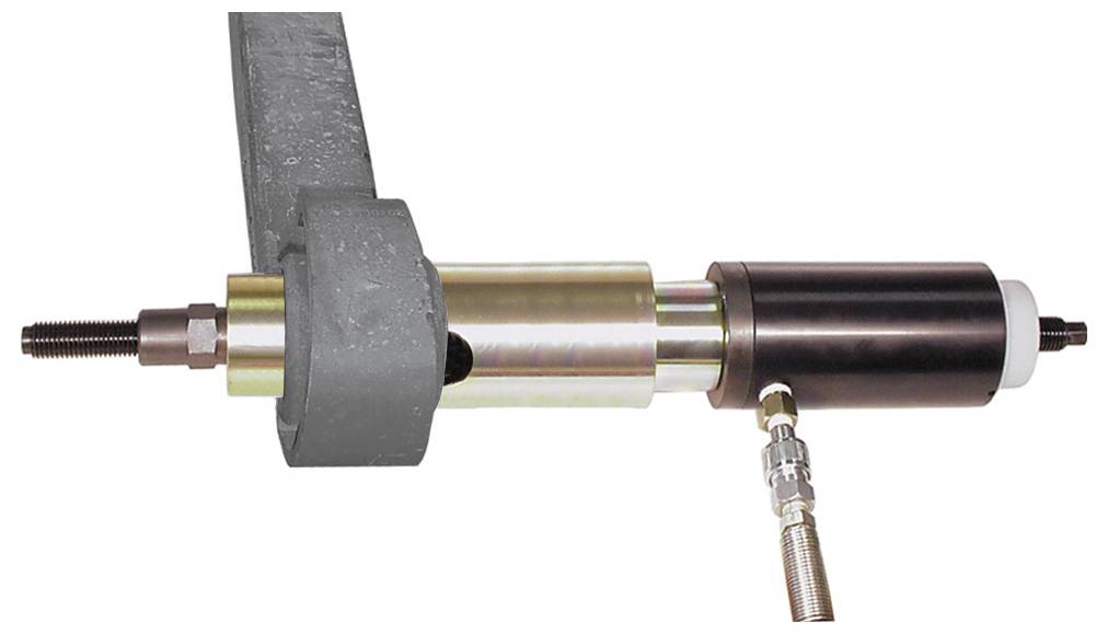 Hydraulický válec s kovovou tyčí a příslušenstvím pracuje v mechanickém systému s viditelným potrubím pro tekutinu a masivní konstrukcí.