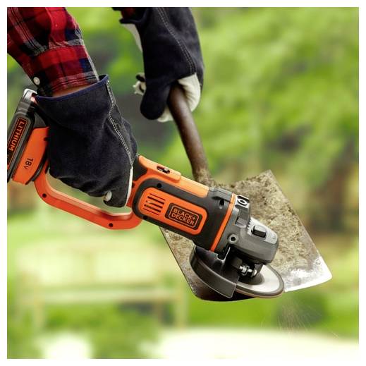 Osoba v rukavicích používá oranžovou úhlovou brusku Black + Decker k nabroušení lopatky proti rozmazanému zelenému venkovnímu pozadí.