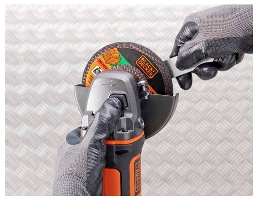 Osoba v rukavicích si vyměňuje disc na úhlové brusce Black+Decker na strukturovaném kovovém pozadí.