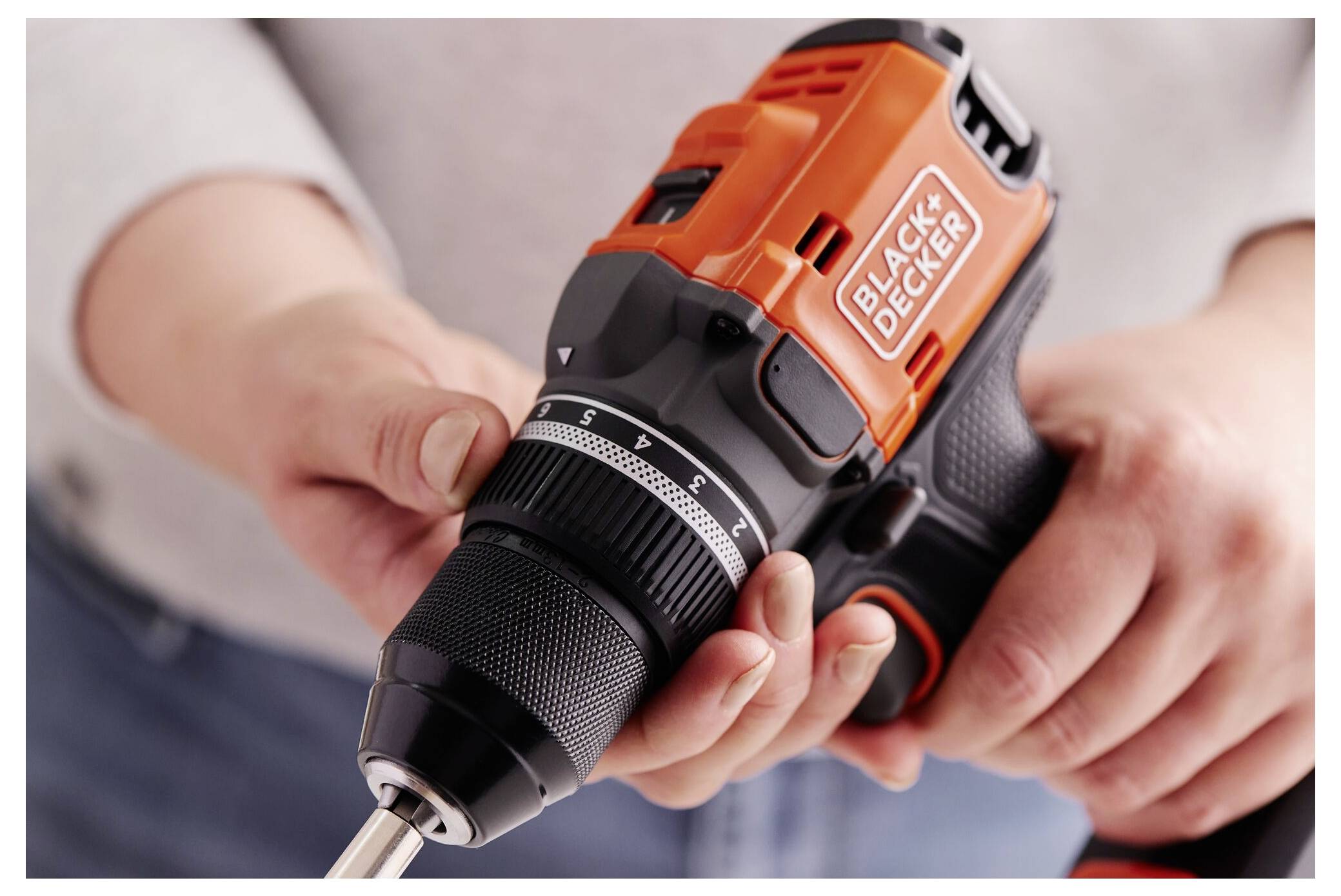 Osoba drží bezšnurový vrták Black & Decker, upravuje jeho nastavení a zdůrazňuje snadnost použití a kvalitu úchopu.