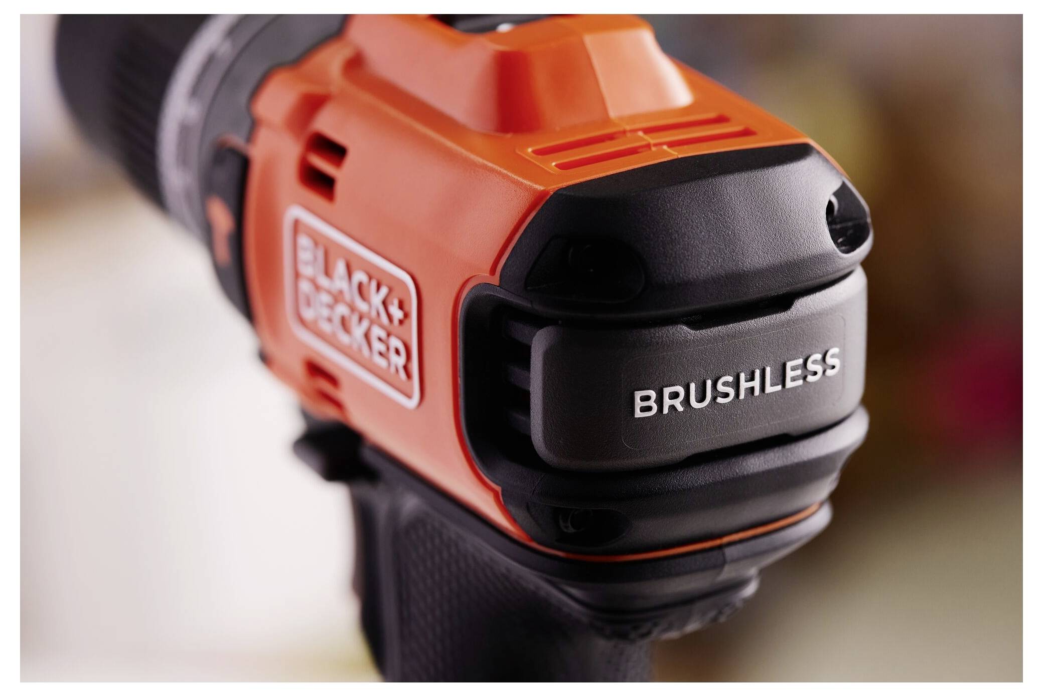 'Detailní pohled na bezuhlíkový vrtací vrták Black+Decker s oranžovým a černým pouzdrem s viditelně zobrazením názvu značky.'