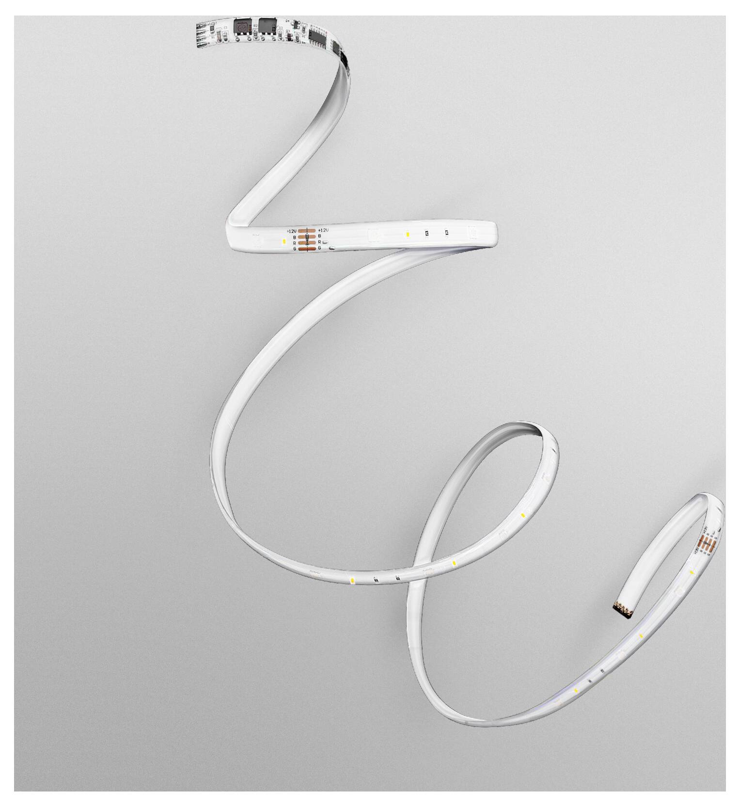 Páska LED svítidel se krčí do spirály na šedém pozadí a předvádí svou pružnost a malé osvětlené sekce.