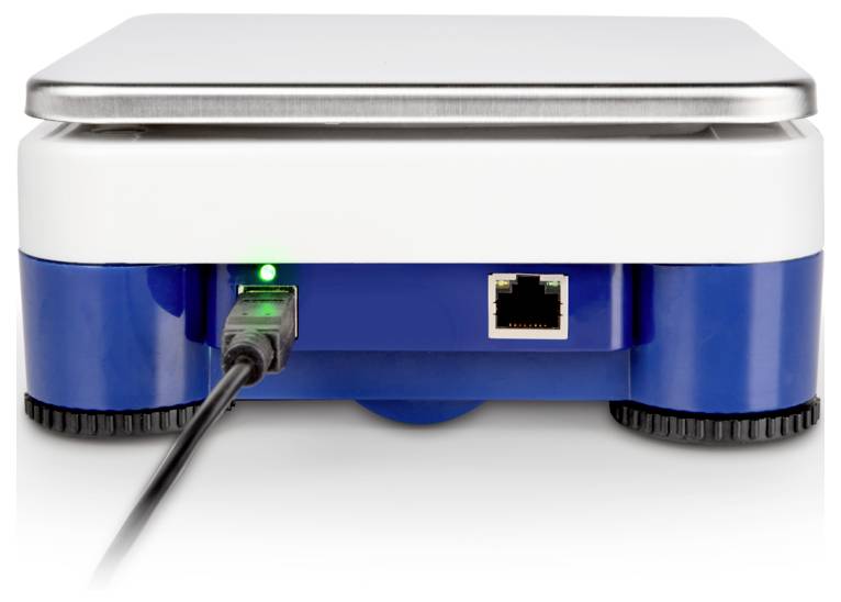 Detailní záběr na zadní stranu elektronického zařízení s připojeným USB kabelem a viditelným portem Ethernet, což ukazuje dostupné možnosti připojení.