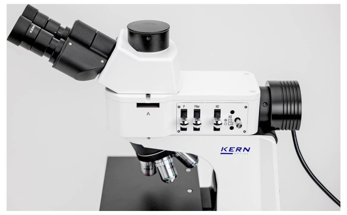 Detailní pohled na laboratorní mikroskop s nastavitelnými kolečky a označenými částmi, používaný pro vědecký výzkum a analýzu.