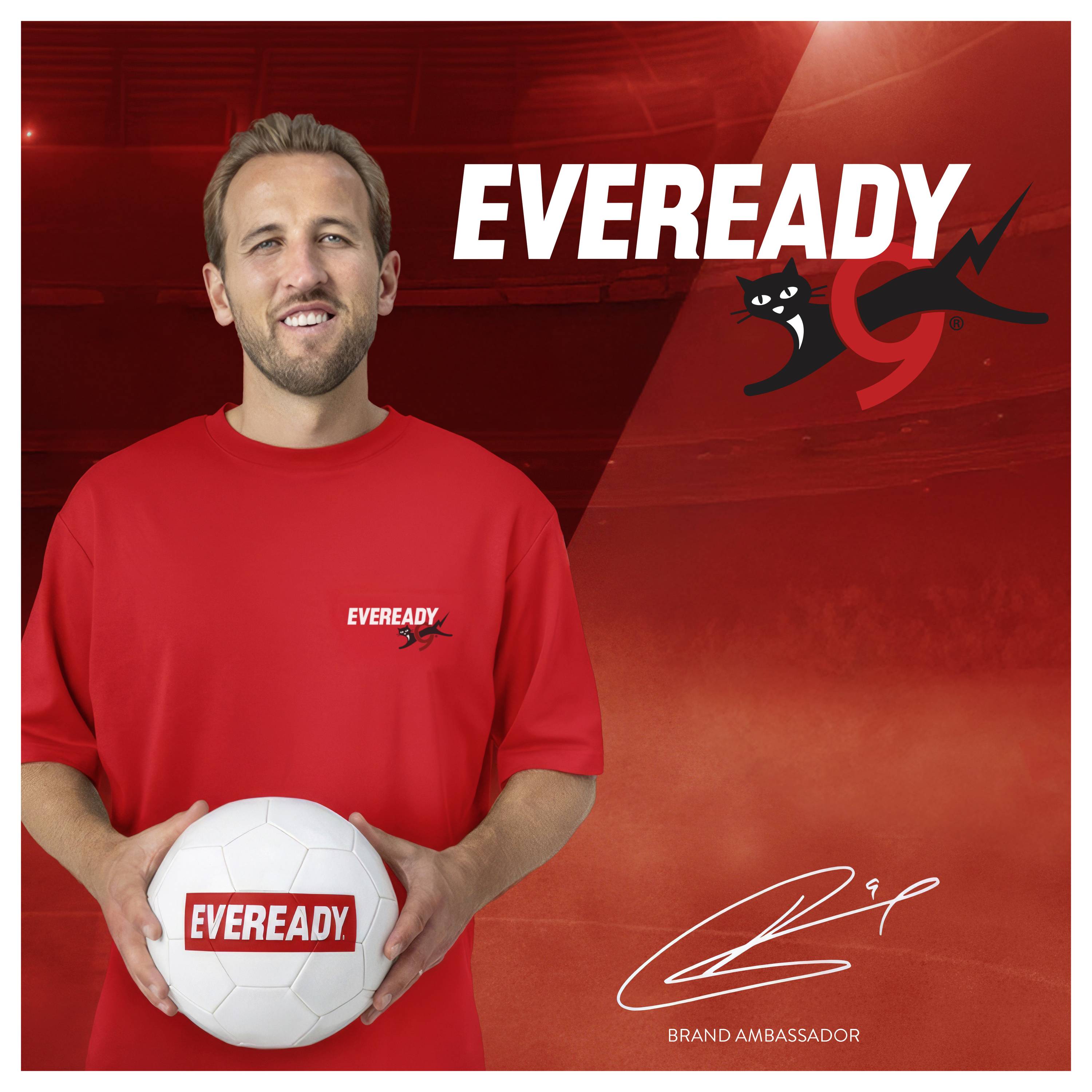 Usměvavý muž v červeném tričku značky "Eveready" drží fotbalový míč. Pozadí zobrazuje logo značky "Eveready" a jeho podpis jako ambasadora značky.
