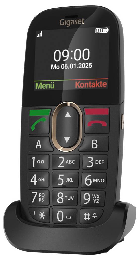 Černý mobilní telefon s velkými tlačítky v nabíjecím stojanu. Displej zobrazuje '09:00 Po 06.01.2025' s možnostmi 'Menu' a 'Kontakty'.
