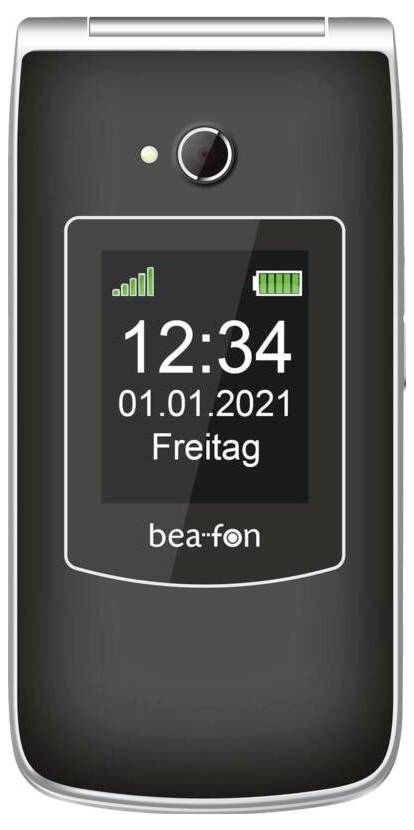 Telefon s klapkou zobrazující digitální displej s časem „12:34", datem „01.01.2021" a dnem „Freitag". Jsou viditelné ikony baterie a signálu.