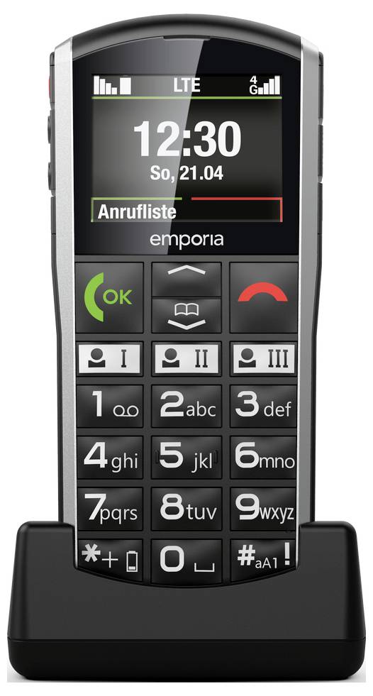 Mobilní telefon s velkými tlačítky, černobílý displej zobrazující „12:30", „So, 21.04" a „Anrufliste". Je v nabíjecím stojanu.