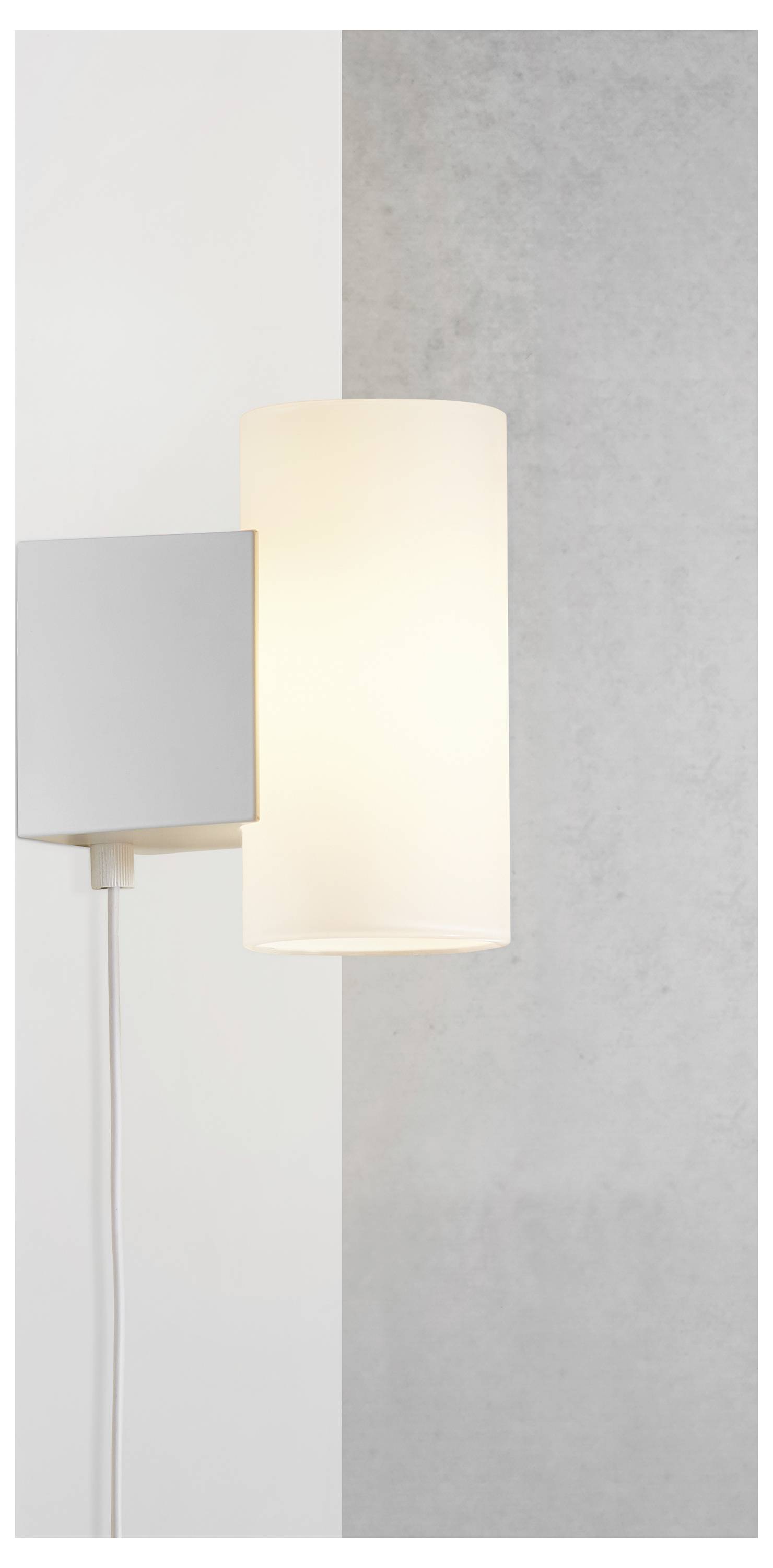 Moderní nástěnná lampa s válcovým stínítkem, vyzařující měkké, teplé světlo na bílém a šedém strukturovaném pozadí.