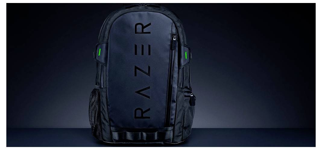 Černý batoh s logem 'RAZER' uprostřed. Batoh má zelené akcenty a několik zipovaných oddílů, vhodný pro herní vybavení.