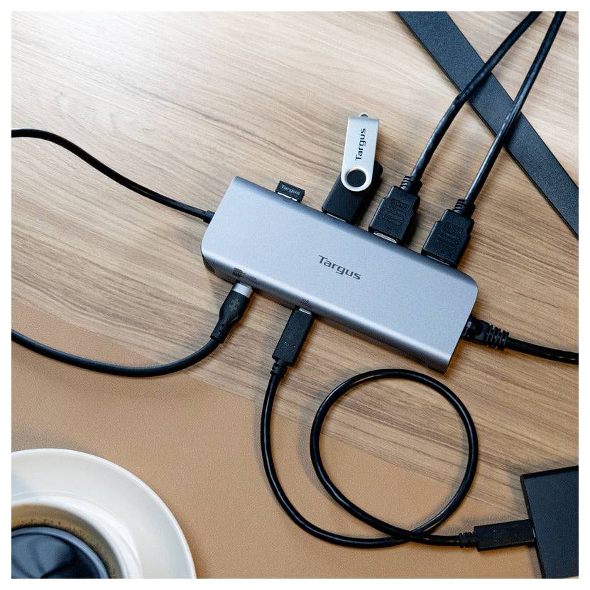 USB rozbočovač s více porty na dřevěném stole připojený k více kabelům a USB disku, usnadňující připojení zařízení.