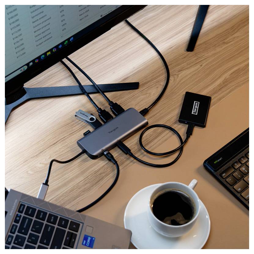 Notebook připojený k více zařízením přes rozbočovač, vedle chytrého telefonu, USB flashdisku, externí pevné jednotky a šálku kávy.