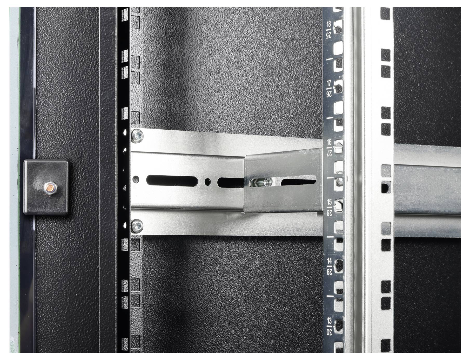 Detailní snímek kovového stojanu nebo rámce skříně serveru zobrazující detailní otvor pro upevnění a zajišťovací držák na strukturovaném pozadí.