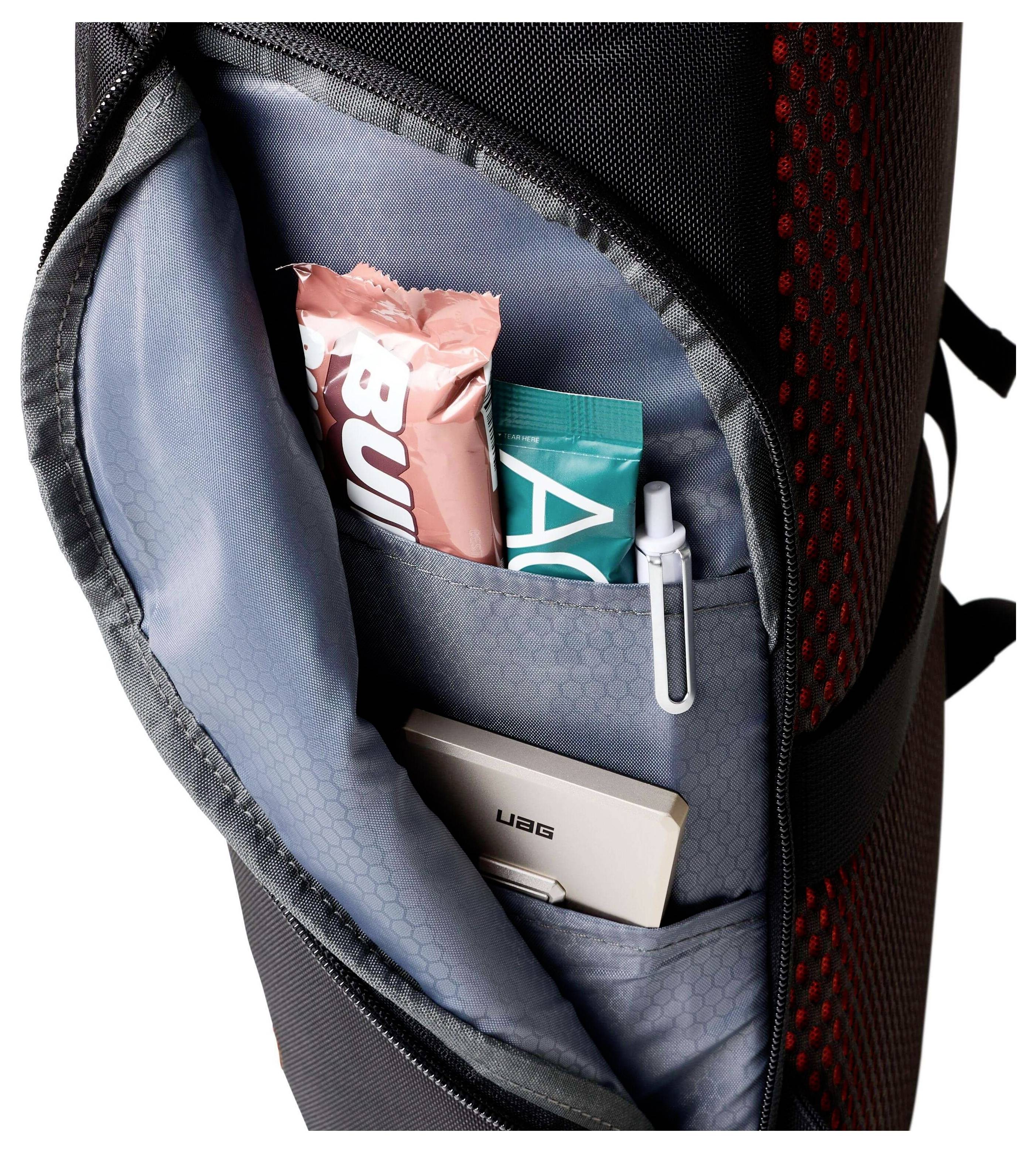 Kapsa batohu obsahující proteinové tyčinky, USB flash disk, pero a modrošedozelený balíček, demonstrující organizaci a skladovací užitečnost.