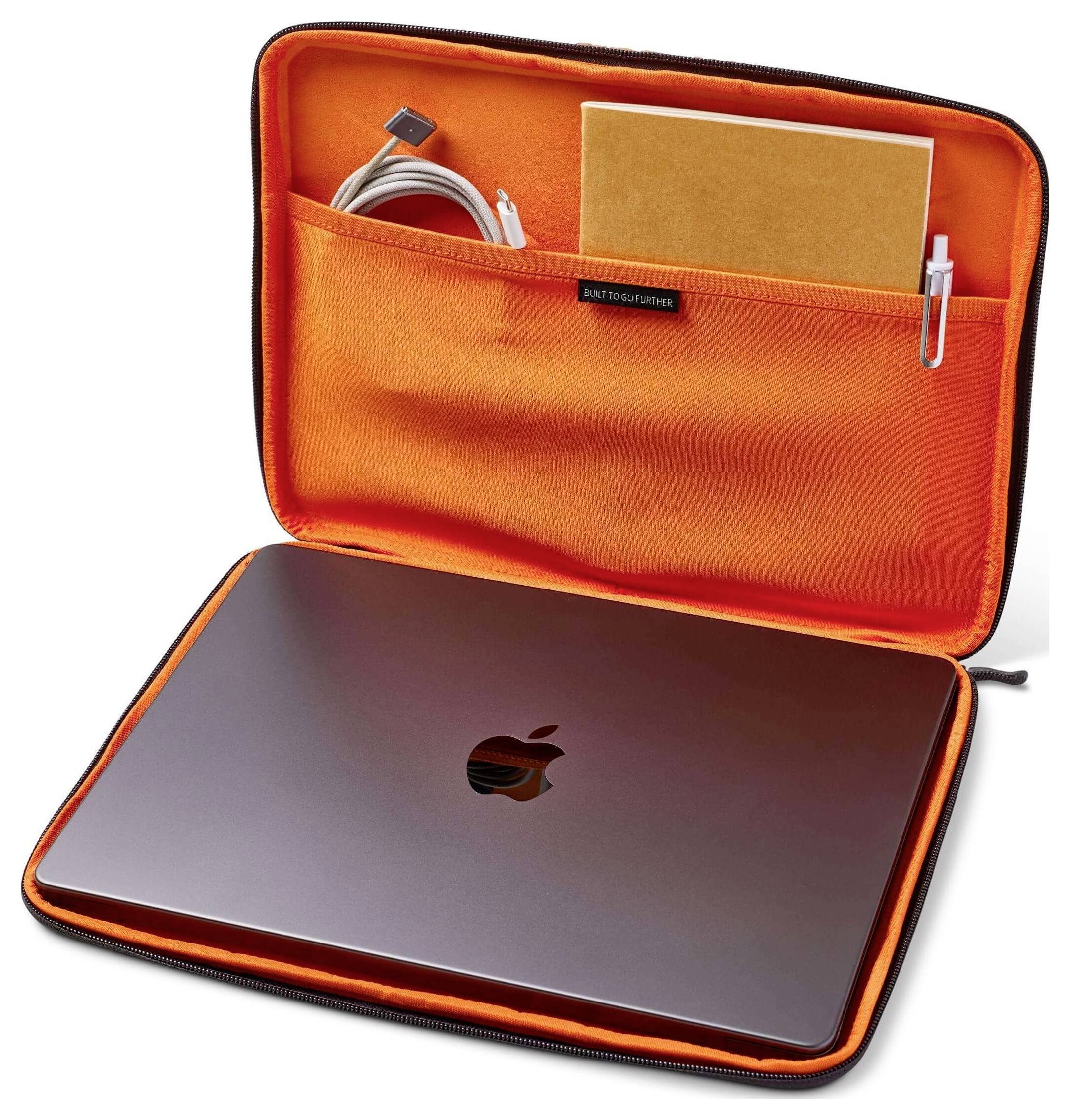Notebook v oranžovém pouzdru s přihrádkami obsahující zápisník, pero a kabel.