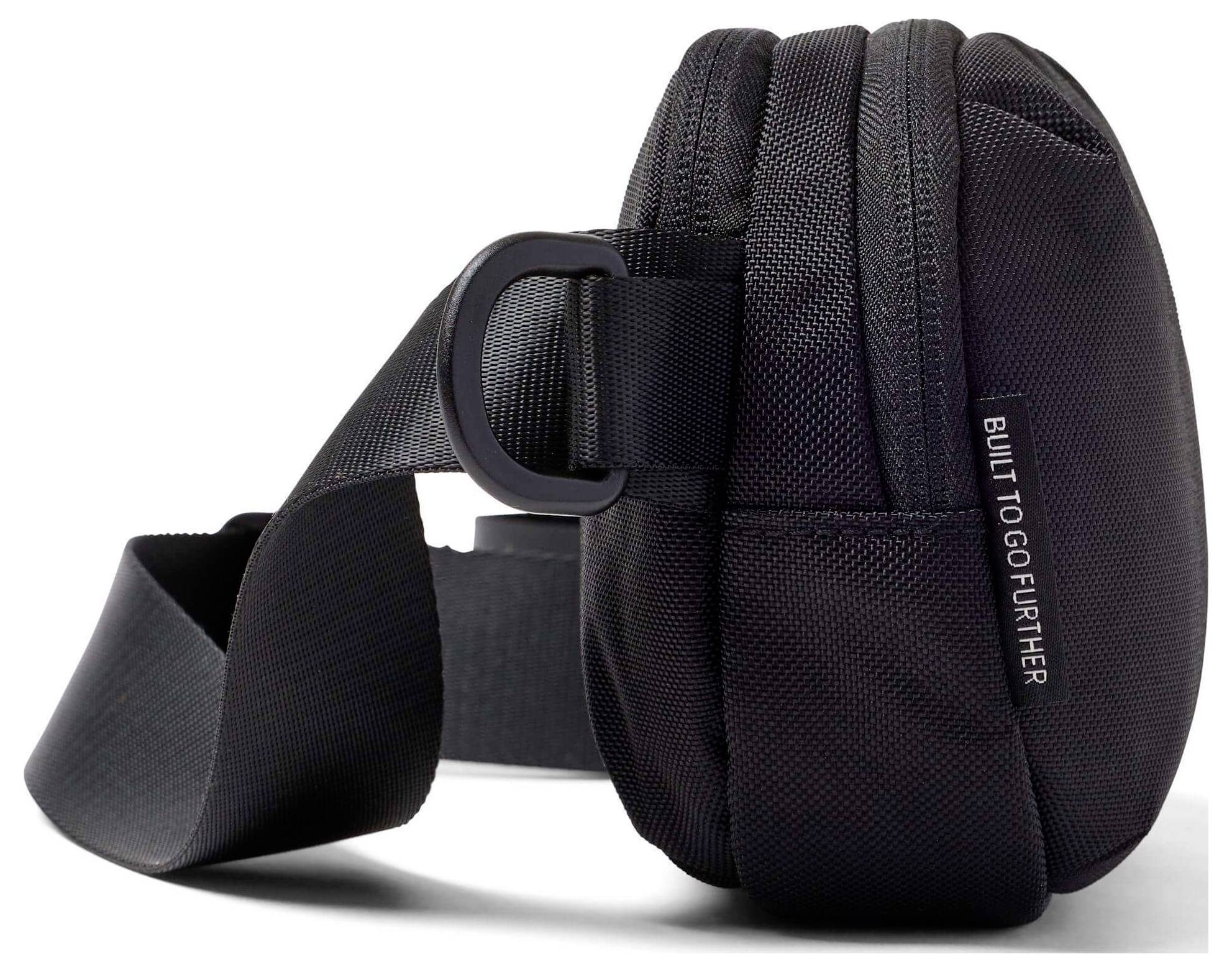 Černá crossbody taška s nastavitelným popruhem, na straně s nápisem "BUILT TO GO FURTHER".