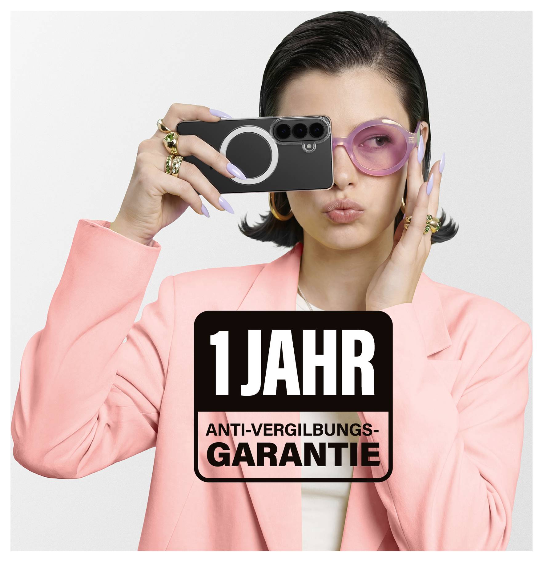 Osoba v růžovém sáku drží telefon s tučným textem "1 rok záruka proti žloutnutí" vpředu. Zpráva propaguje záruku produktu.