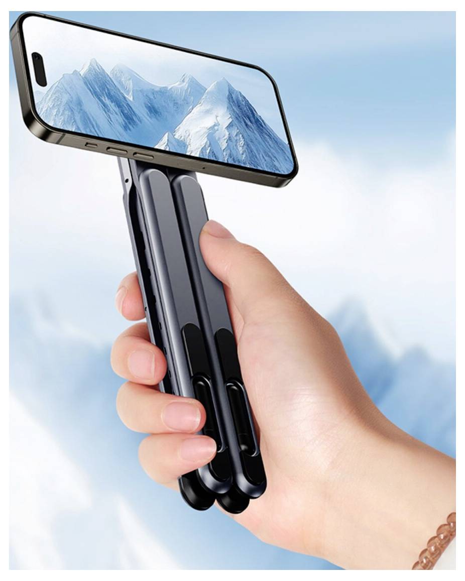 Ruka drží selfie stick ve stylu motýlího nože se smartphonem připevněným na spici, který zobrazuje horskou krajinu na displeji.