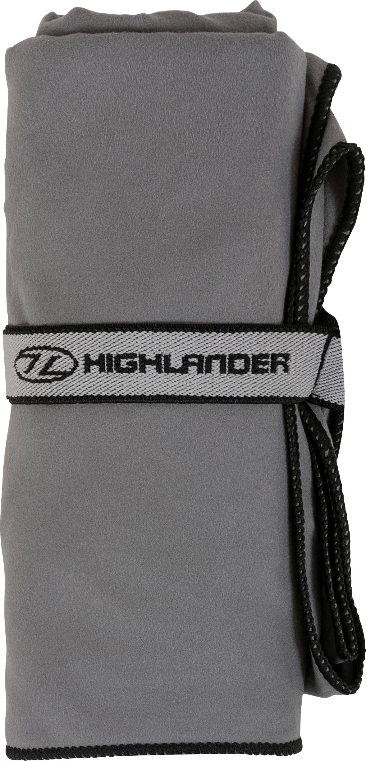 Šedý srolovaný microfibrový ručník zajištěný černým elastickým páskem s nálepkou „Highlander".