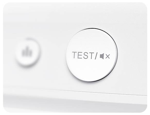 Detailní snímek bílého tlačítka se zatímco "TEST/MUTE" na elektronickém zařízení. Další tlačítko je rozostřeno v pozadí.