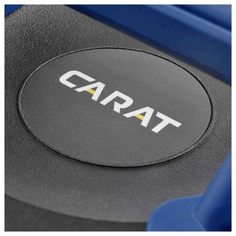 Obrázek ukazuje detailní záběr na černé kruhové logo s nápisem "CARAT" v tučných bílých písmech, se žlutým akcentem, na tmavém povrchu.