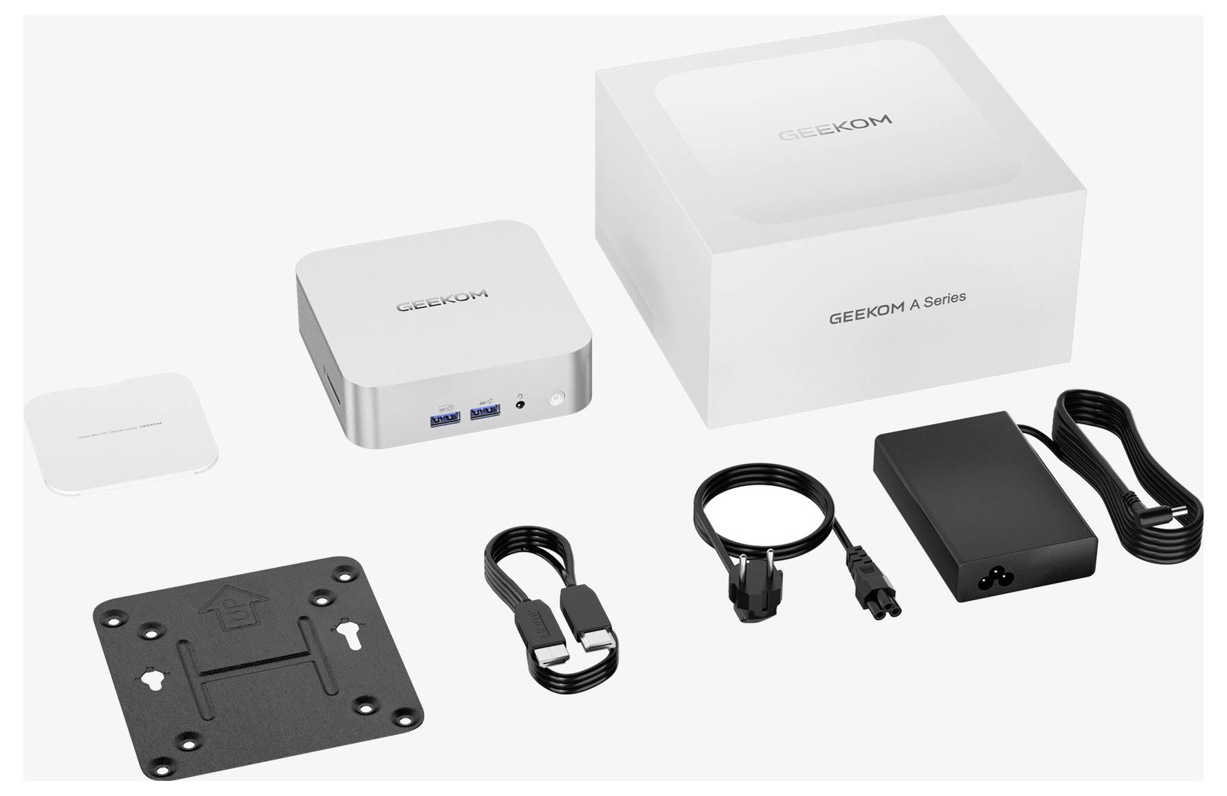 GEEKOM řada A mini PC sada s kompaktním počítačem, adaptérem napájení, montážní deskou, kabelem, HDMI kabelem a malou krabicí s příslušenstvím na bílém pozadí.