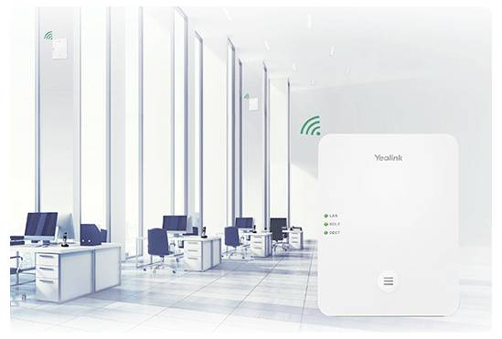 Moderní kancelářský prostor s řadami stolů a počítačů, v popředí je vidět zařízení Yealink, což poukazuje na zaměření na komunikační technologii.